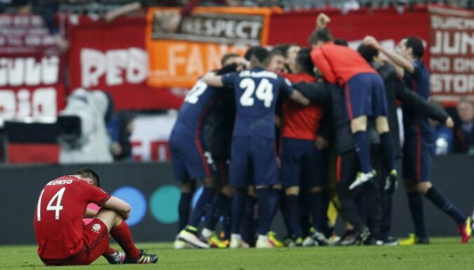 Bayern s Xabi Alonso sits on the pitch as Atletico players celebrate