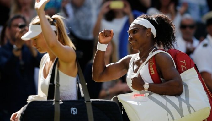 Serena Williams (R) pumps her fist as she leaves the court with Russia s Maria Sharapova