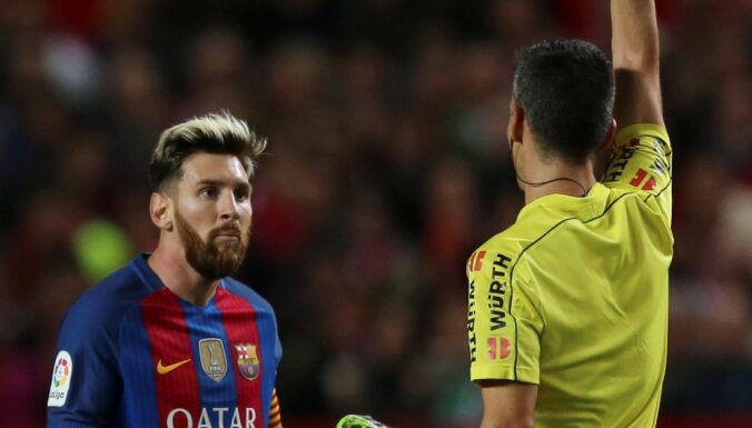 Barcelona s Lionel Messi receives a yellow card